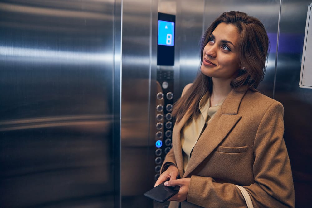 A woman in a smart elevator, holding a smartphone, showcasing modern vertical transportation technology.