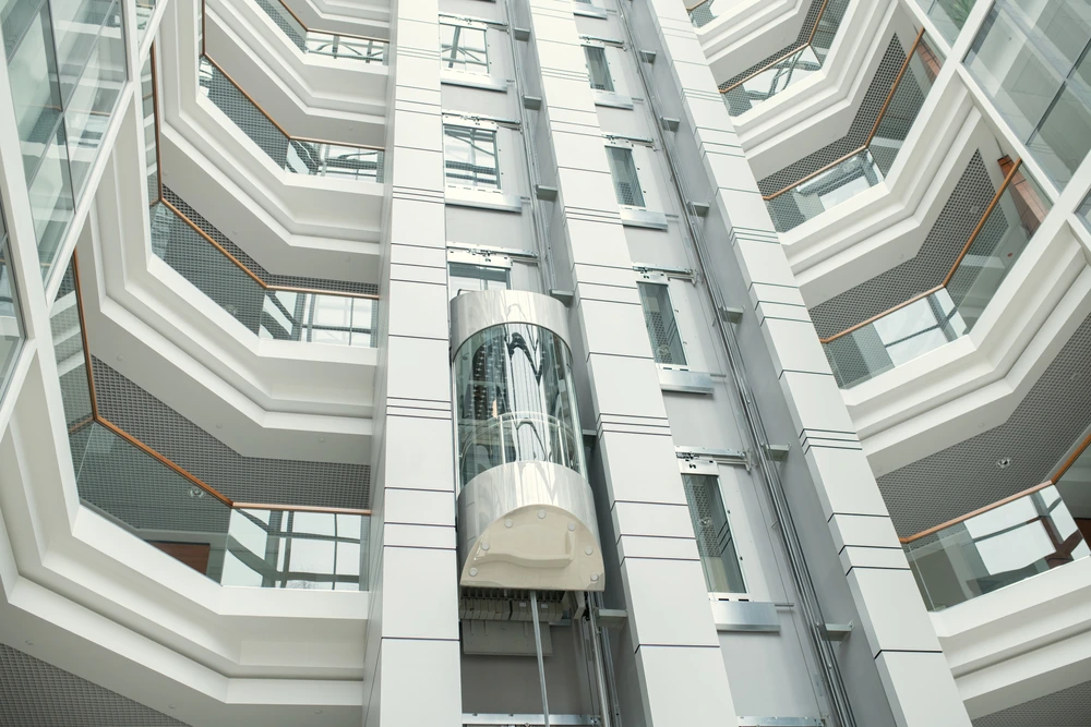 Modern glass shaft with Energy-Efficient Elevators inside a high-rise building showcasing a sleek, futuristic vertical transport system.