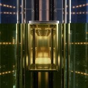 Modern glass elevator ascending through a sleek skyscraper at dusk, showcasing advanced safety and urban luxury in high-rise architecture.