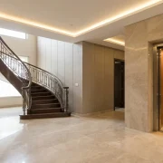 Comparison between a modern home elevator and a traditional stairlift in a Pakistani residential interior, highlighting mobility and accessibility solutions for elderly and disabled family members.